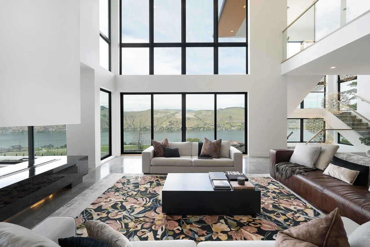The living room’s patterned rug and sofas facing floor-to-ceiling windows onto the lake