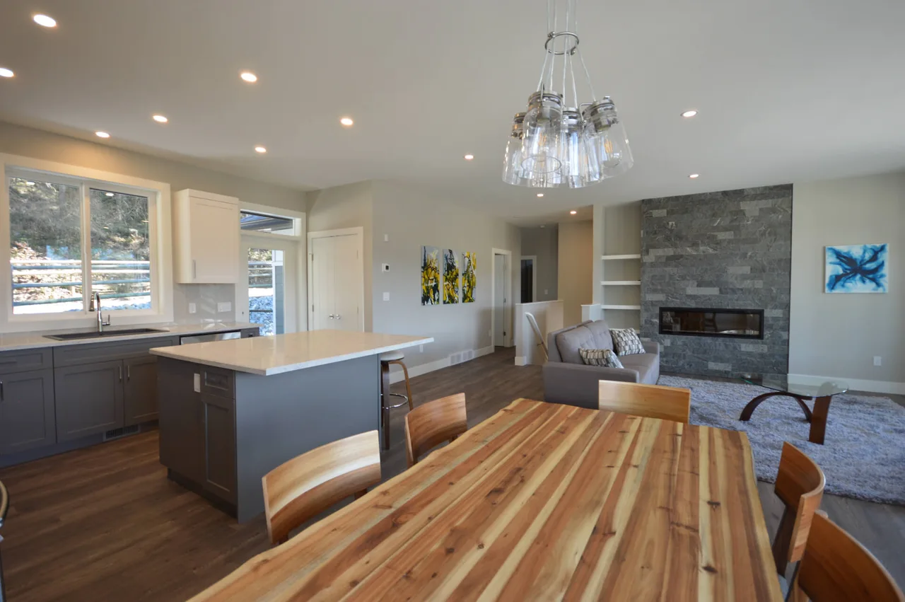 The kitchen’s island and dining table under a glass pendant, open to the living room