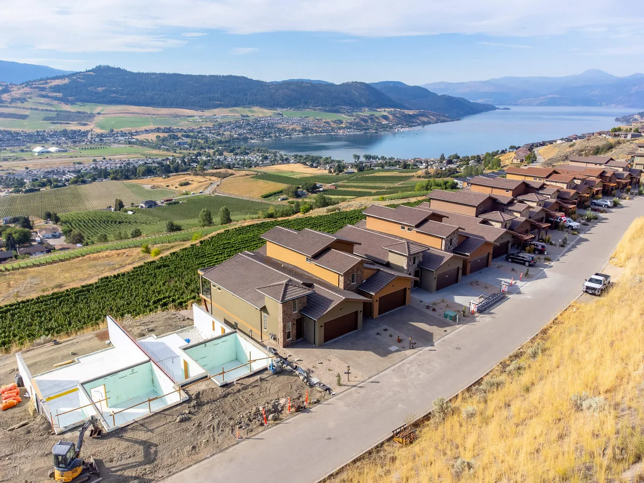 An aerial view of the Vineyard Way duplexes above the vineyard, with Okanagan Lake beyond