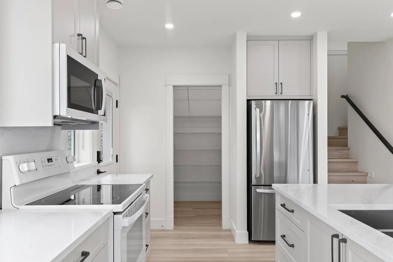 The kitchen, pantry and stairs, with white shaker cabinets
