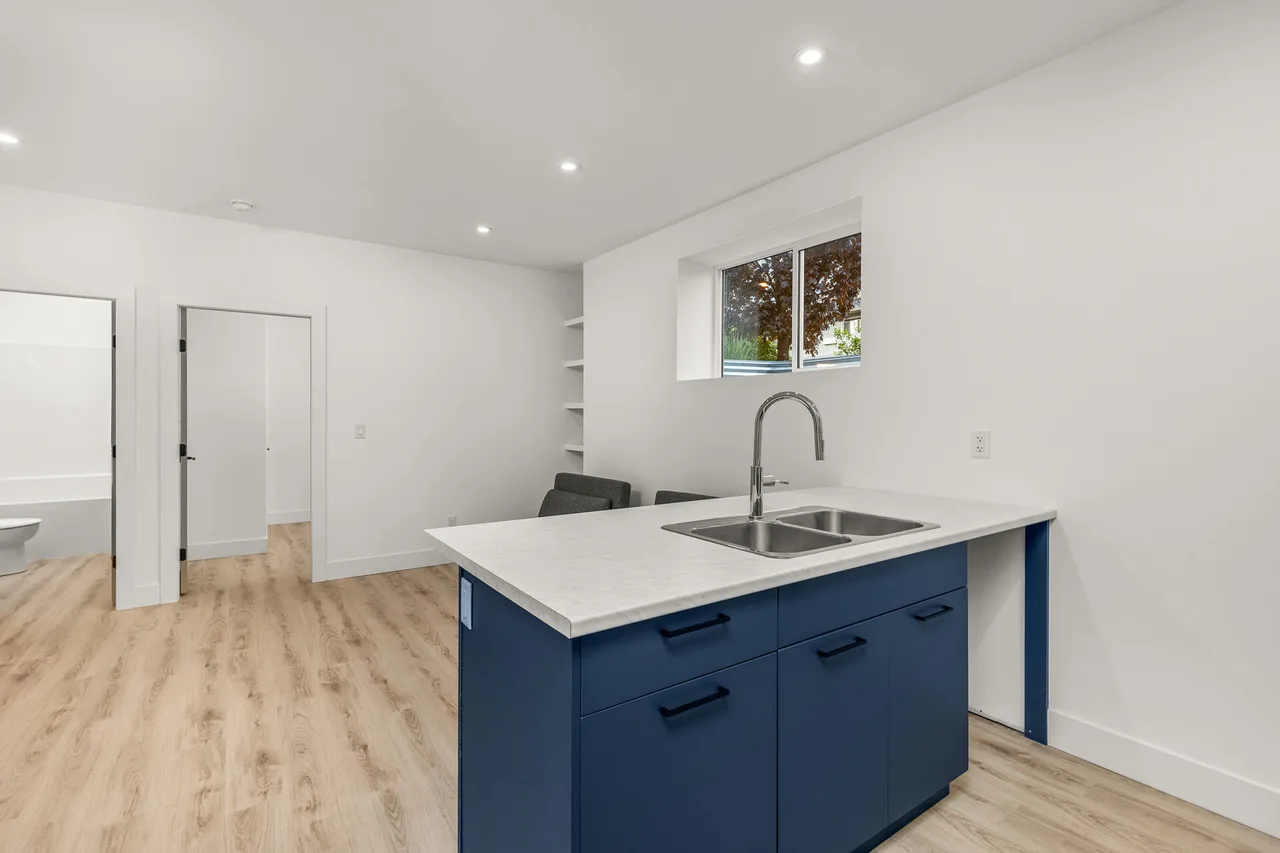 A navy kitchen peninsula with a double sink in the basement suite