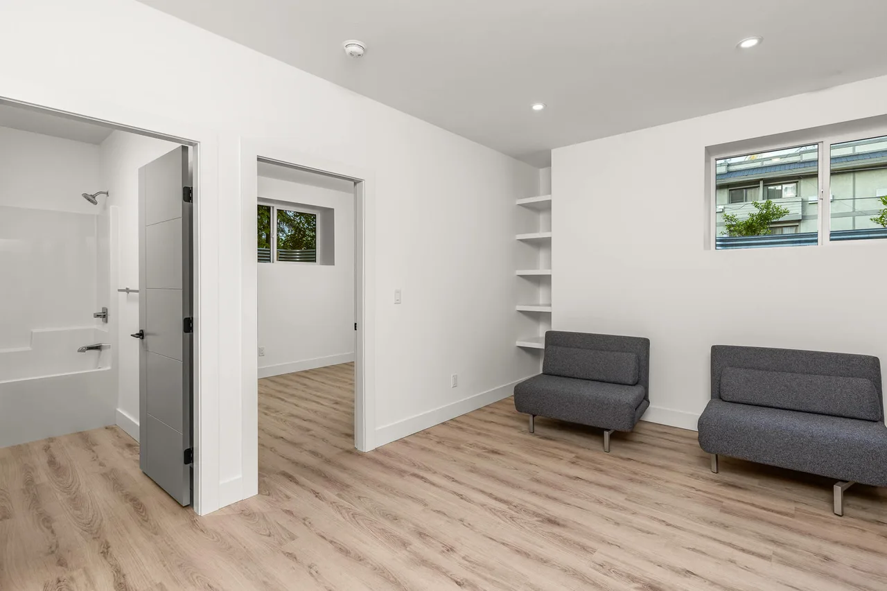 A sitting area with built-in shelves and doors to a bedroom and bathroom